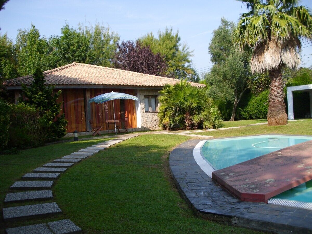 Ein Garten mit Swimmingpool, einem Kiesweg und einer Holzterrasse mit Gartenmöbeln.