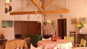 A cozy room with wooden beams, a dining table with chairs, and a television on the wall. - Charming chalet  with private pool and around to beaches (Espargo/Santa Maria da Feira)