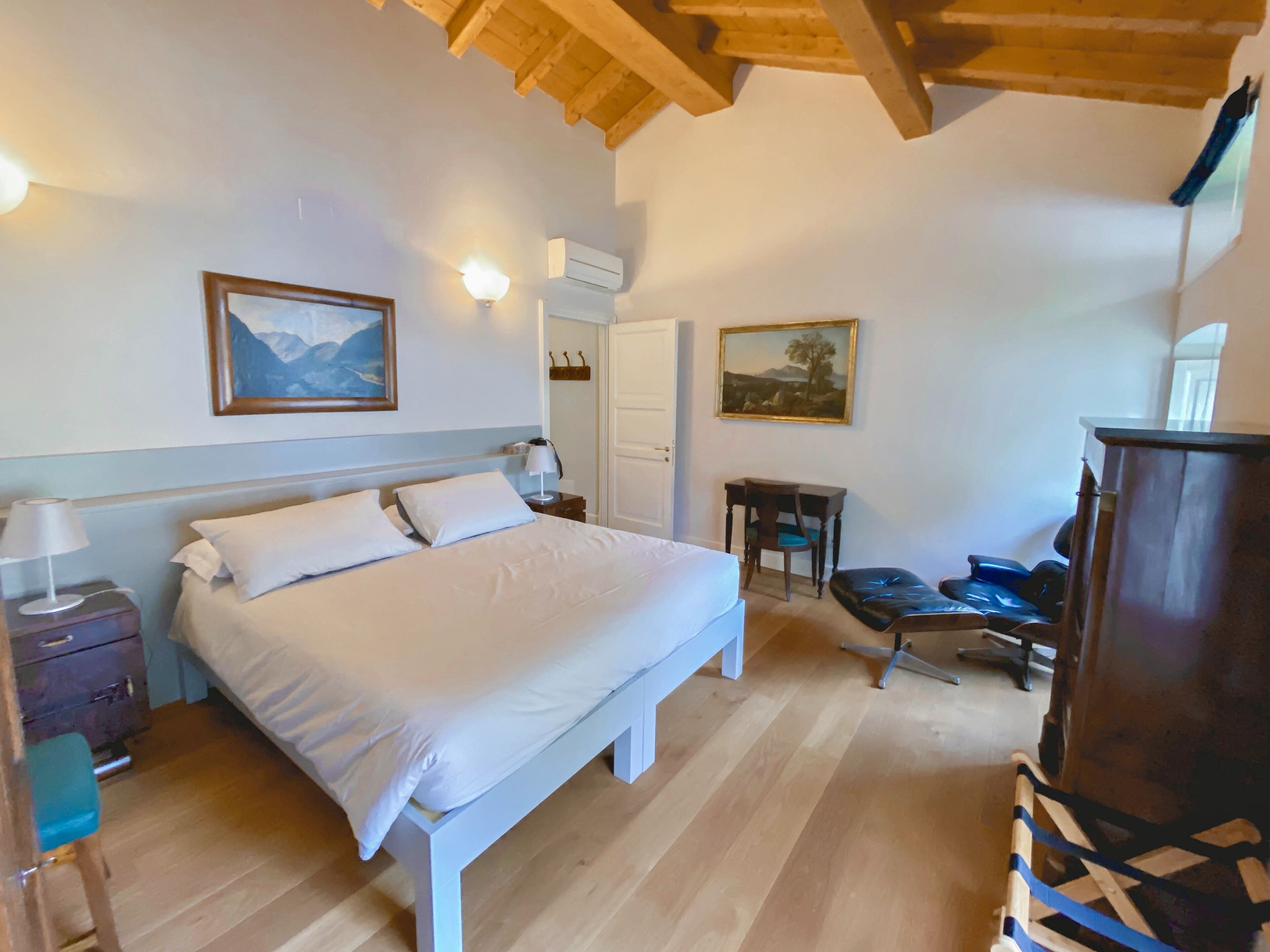 Un dormitorio con cama, mesitas de noche, escritorio y silla.