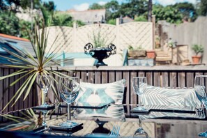 A patio with a table set for dining, featuring a glass-top table, metal chairs, and a decorative plant.