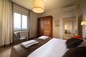 Ein Hotelzimmer mit einem großen Bett, einem Holzschrank, einem Stuhl und einem Fenster mit Vorhängen.