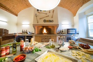 Eine Küche mit Ziegeldecke, Kamin und verschiedenen Kochutensilien sowie Zutaten auf der Arbeitsplatte.