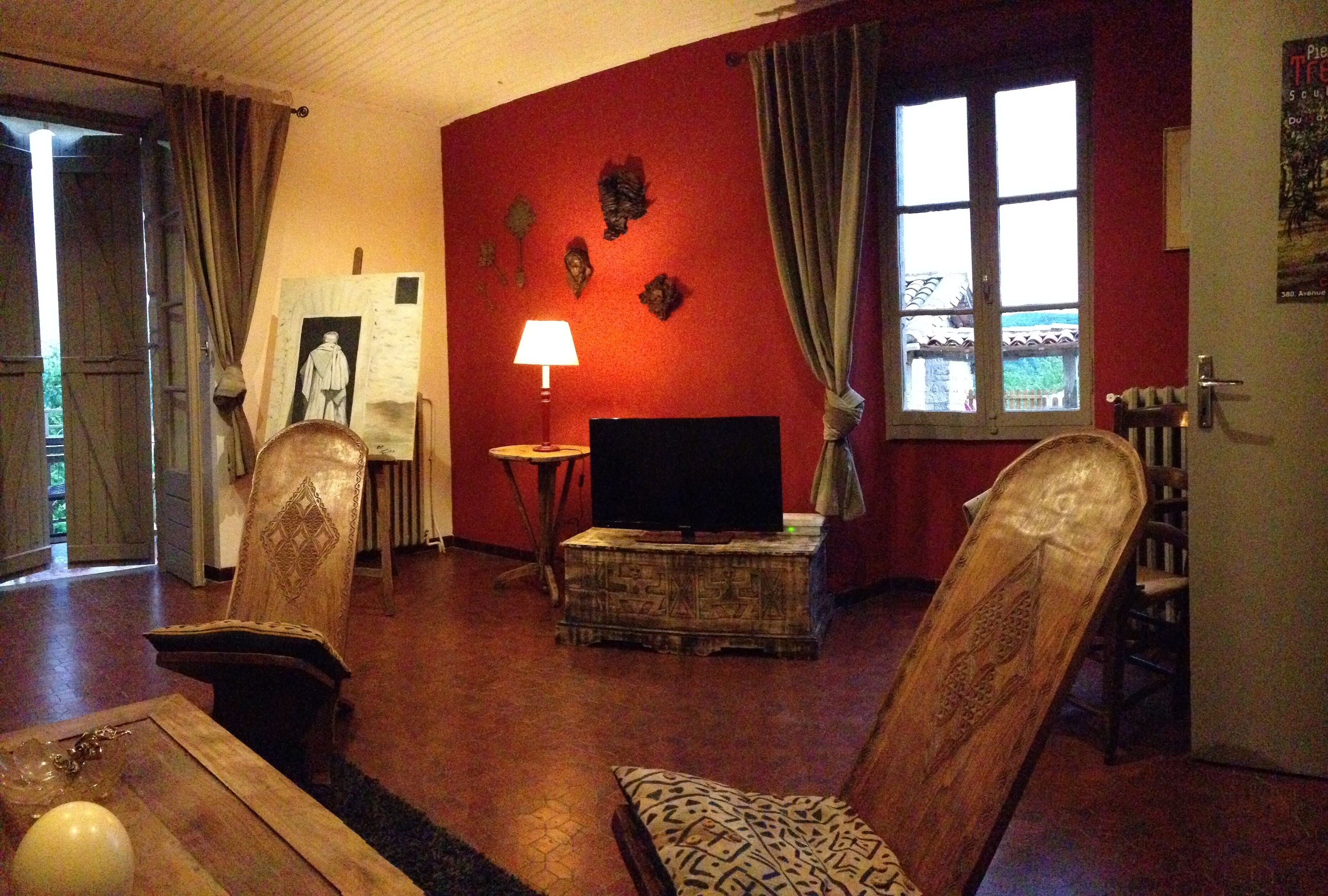 Una sala de estar con televisor, una mesa con un adorno y un sillón con cojín estampado.