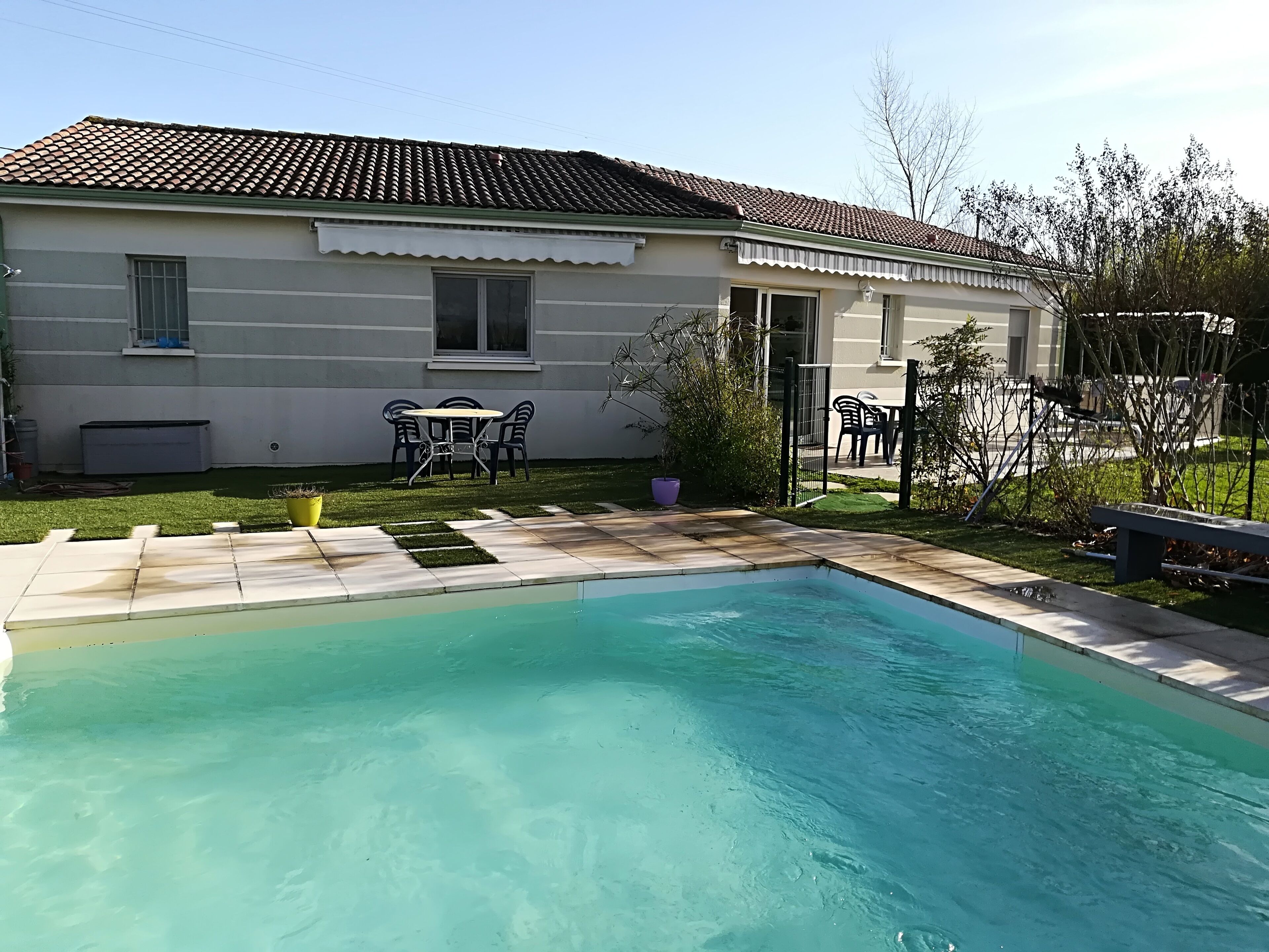 A residential property with a swimming pool, a patio with outdoor furniture, and a well-maintained lawn.