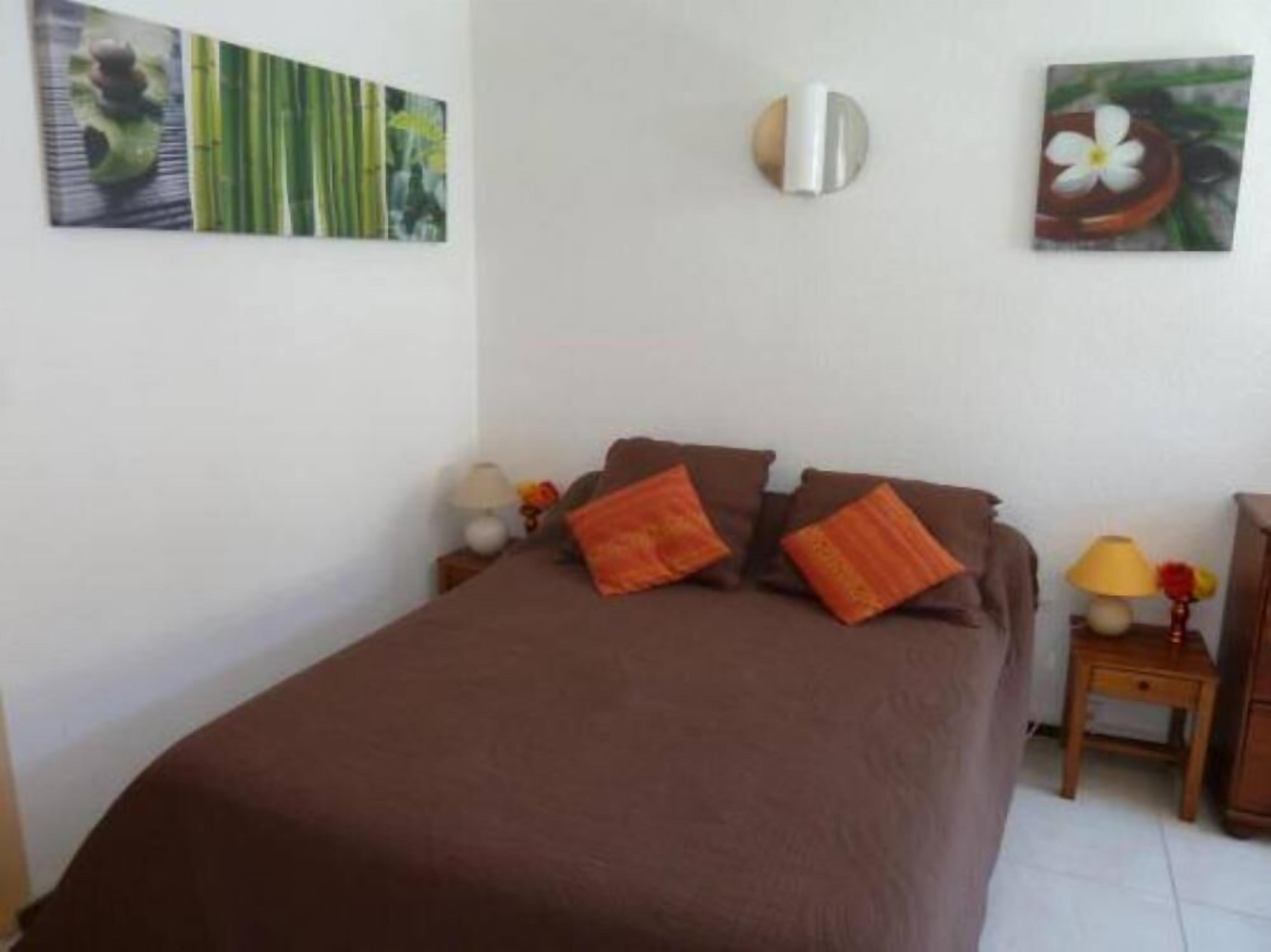 Une chambre à coucher avec un lit, des oreillers, une table de chevet avec une lampe et des œuvres d’art murales.