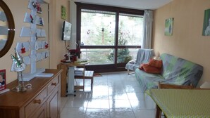 Un soggiorno con un'ampia finestra, un divano, una televisione e un mobile in legno.
