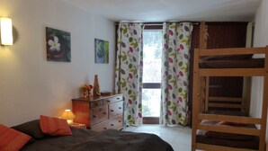 Una camera da letto con un letto a castello, una cassettiera, una lampada e una finestra con tende.