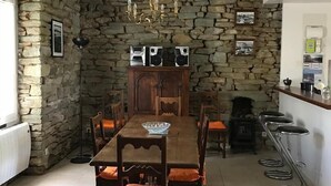 A dining area with a stone wall, wooden table, and chairs. - Groix: Authentic fisherman's house close to any convenience (Groix)
