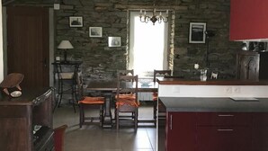 A kitchen with a stone wall, wooden furniture, and a dining area with chairs and a table. - Groix: Authentic fisherman's house close to any convenience (Groix)