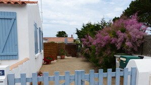A gated courtyard with a white building, a wooden fence, and a flowering tree. - house / villa - LA GUERINIERE (La Guérinière)