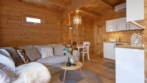 A cozy cabin interior with a wooden ceiling, a sofa, a dining table, and a kitchen area. - The Sea Lodge - Free Parking (Zandvoort)