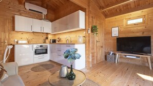 A wooden cabin interior with a kitchen, dining area, and living room. - The Sea Lodge - Free Parking (Zandvoort)