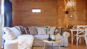 A cozy wooden cabin interior with a sofa, round coffee table, and a dining area. - The Sea Lodge - Free Parking (Zandvoort)
