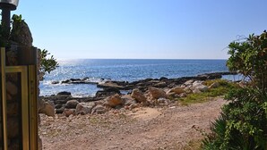 Ein felsiger Küstenpfad, der zum Meer führt, mit freiem Blick auf den Ozean.