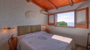 Ein Schlafzimmer mit Bett, einem Fenster mit Blick, einem dekorativen Kopfteil und Wandleuchten.