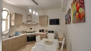 A modern kitchen with a dining area, stainless steel appliances, and a flat-screen TV.