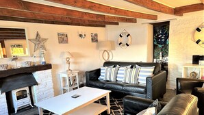 A cozy living room with a fireplace, a black leather sofa, a white coffee table, and a patterned rug. - Seaweed Cottage in Fowey overlooking the beach with a garden and a parking space (Fowey)