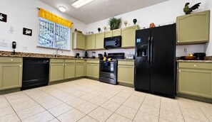 A kitchen with green cabinets, a black refrigerator, a microwave, and a dishwasher. - BlueLakeView Villa – Private Pool & Spa, Stunning Lake Views, BBQ & Games Room (Clermont)