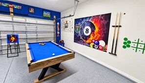 A pool table in a room with a blue wall, a large painting, and a blue pool cue stand. - BlueLakeView Villa – Private Pool & Spa, Stunning Lake Views, BBQ & Games Room (Clermont)