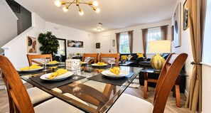 A modern dining area with a glass table, wooden chairs, and yellow napkins.