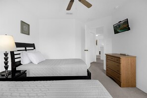 A bedroom with two beds, a wooden dresser, a nightstand with a lamp, and a ceiling fan. - BlueLakeView Villa – Private Pool & Spa, Stunning Lake Views, BBQ & Games Room (Clermont)