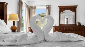 Quarto de hotel com cama, luminária, cômoda e espelho.