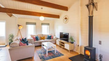 Un salon comprenant un ensemble de canapés, un téléviseur, une cheminée et un ventilateur de plafond.