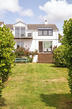 Ein zweistöckiges Haus mit Veranda, überdachter Terrasse und kleinem Garten.