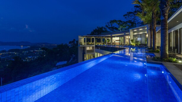 Ein moderner Infinity-Pool mit Blick auf eine Stadtlandschaft im Abenddämmerung.