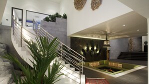 Ein modernes Interieur mit einer Treppe, einer grünen Sofaecke und einem roten Teppich mit Muster.