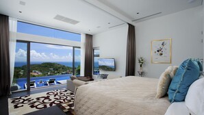 Ein modernes Hotelzimmer mit einem großen Bett, einem Flachbildfernseher, einem Balkon mit Meerblick und einem großen Fenster.