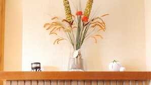 A brick fireplace with a flat-screen TV, a vase with flowers, and a clock on the wall.