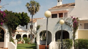 A courtyard with white buildings, arches, and a palm tree.