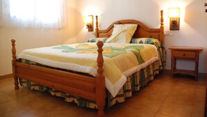 A neatly made bed with a wooden frame, two bedside lamps, and a small bedside table.