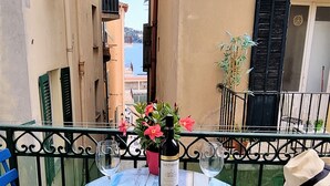 A table set on a balcony with a tablecloth, a bottle of wine, and glasses. - Holiday one bedroom apt, in heart of old town, lovely sea view (Villefranche-Sur-Mer)