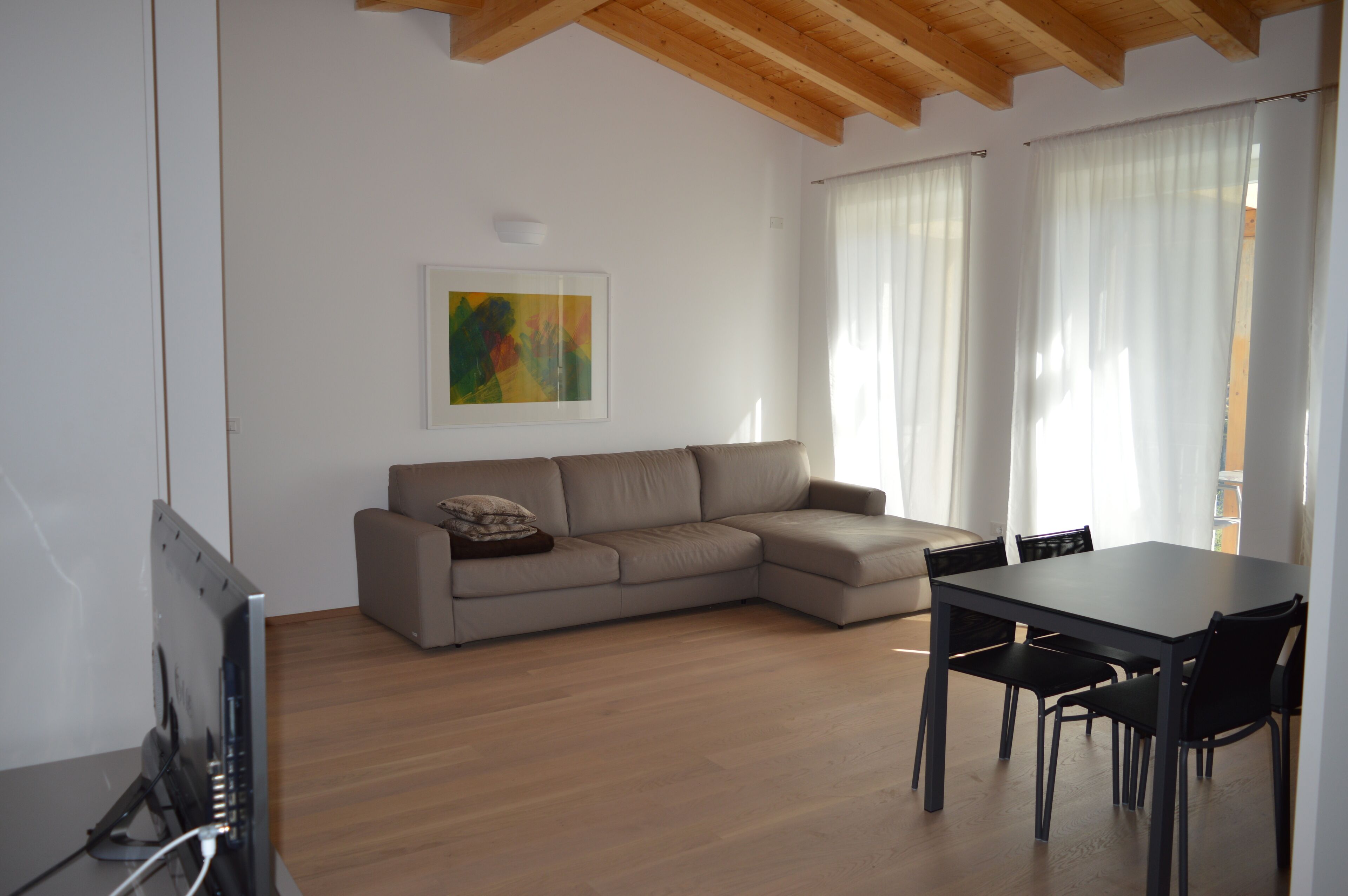 Uma sala de estar moderna com sofá, mesa de jantar com cadeiras e uma televisão de tela plana.