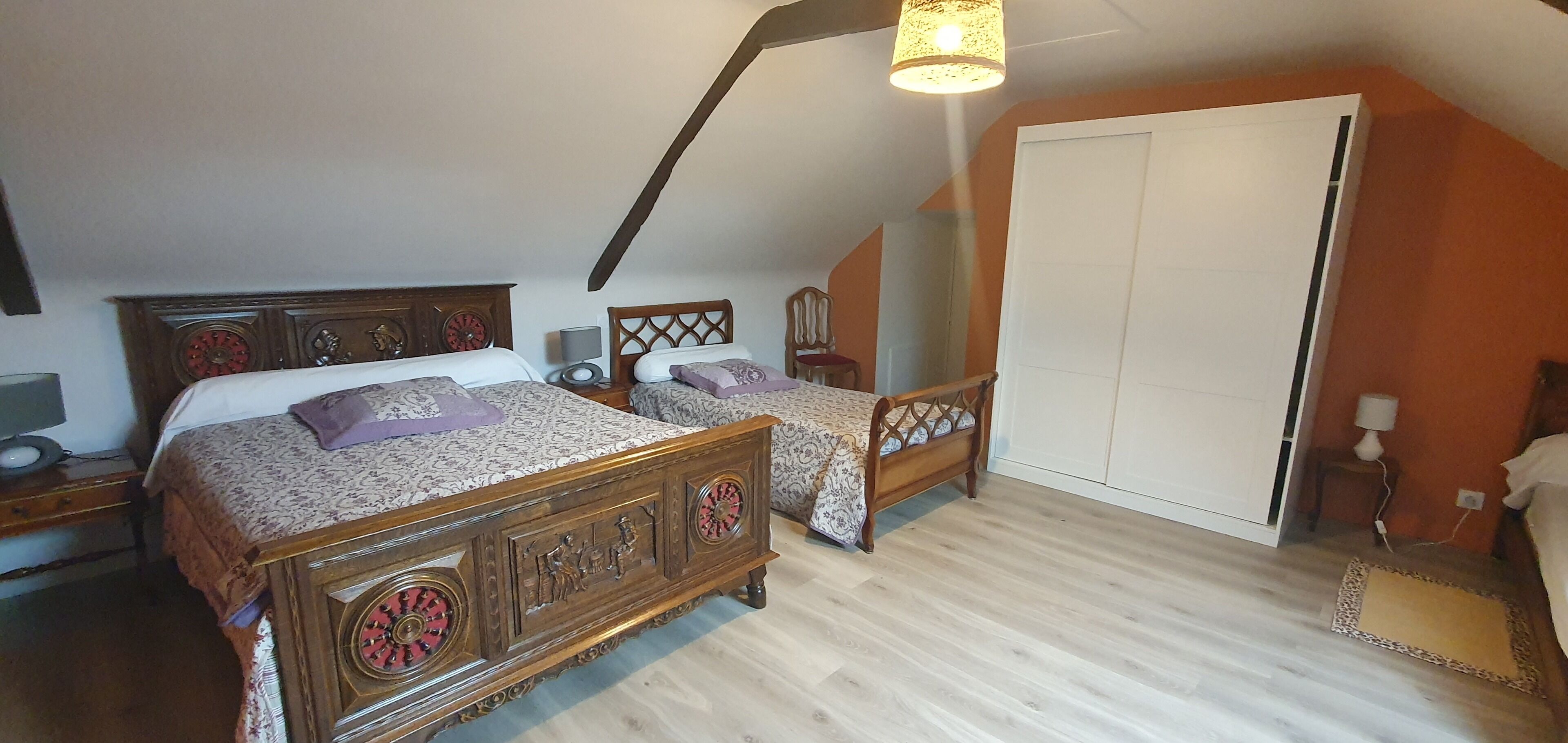 A bedroom with two wooden beds, a wardrobe, and a sloped ceiling.