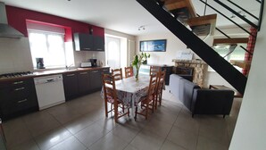 A modern kitchen with a dining area, a staircase, and a living room. - Country Cottage / Gite - SAINT GOUENO (Le Mené)