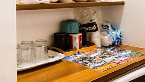 Een keuken met houten planken waarop keukengerei, een waterkoker en een koffiezetapparaat staan.