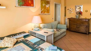 Een knus ingerichte kamer met een bed, een slaapbank, een tafeltje met een lamp en een kast.