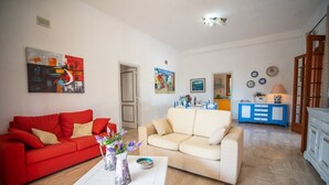 A living room with a red sofa, a beige sofa, a white coffee table, and a blue cabinet.