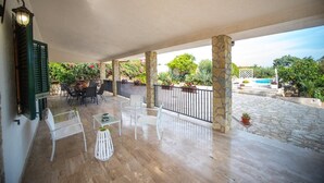 An outdoor patio with stone columns, a pool, and a dining area with chairs and tables.