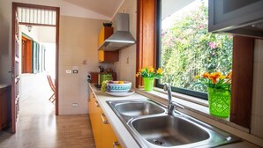A modern kitchen with two sinks, a stove, and a window with a view of greenery.