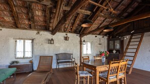 A rustic room with a wooden dining table, chairs, a bench, and a ladder.