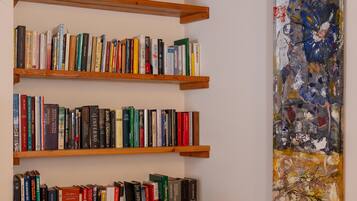 A room with wooden bookshelves filled with books, a wooden ceiling, and a large abstract painting on the wall.