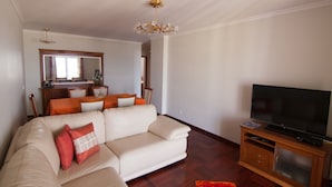 Een woonkamer met een bank, een televisie en een houten kast.