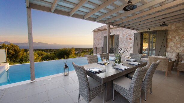 Un área de comedor con vista a una piscina, mobiliario exterior y un edificio de piedra.