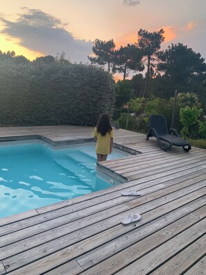 A wooden deck with a swimming pool, a lounge chair, and a child standing by the pool. - House / Villa - Lacanau Océan (Lacanau)