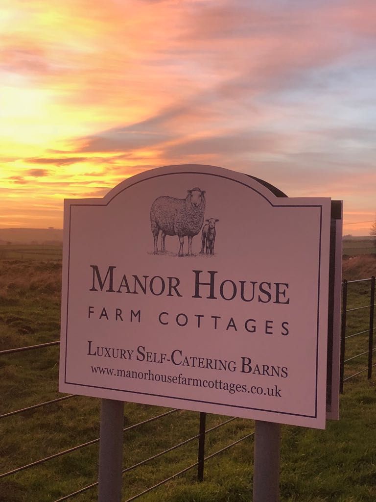 A sign for Manor House Farm Cottages advertising luxury self-catering barns.
