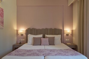 A double bed with a floral bedspread, two bedside lamps, and a nightstand with a glass of water.